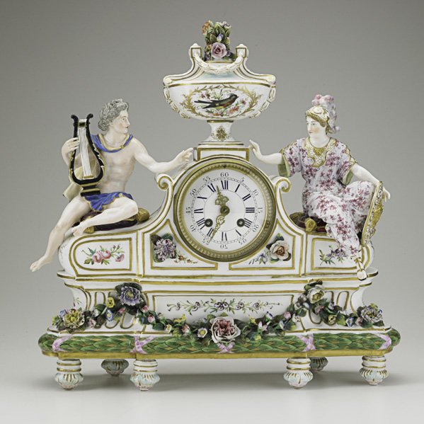 GERMAN PORCELAIN CLOCK: GERMAN PORCELAIN CLOCK; Double figure with urn top, French time and strike movement, 19th c.; 17 1/2'' x 17 1/2'' x 4 1/2''