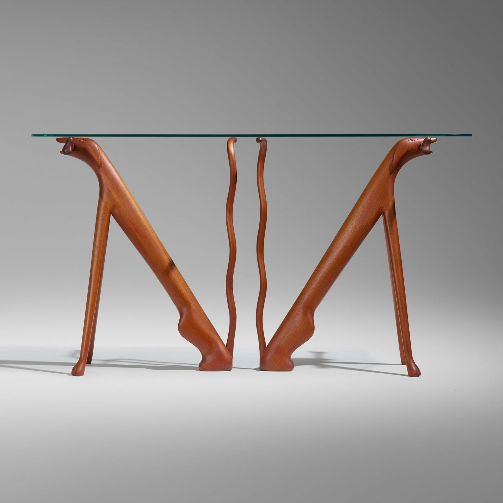 Judy Kensley McKie, Table with Dogs: Judy Kensley McKie Table with Dogs USA, 1979carved and laminated mahogany, glass 34.5 h x 62 w x 18 d in (88 x 157 x 46 cm) Carved signature and date to underside of each base 'JKM 1979'. <