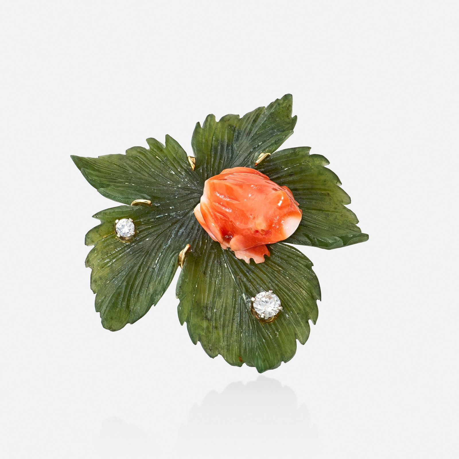 Coral, nephrite, and diamond brooch: Coral, nephrite, and diamond brooch The carved coral frog sitting atop a carved nephrite leaf, enhanced by round brilliant-cut diamonds 14k yellow gold 1.75 x 1.625 in; Gross weight 8.4 dwts This work