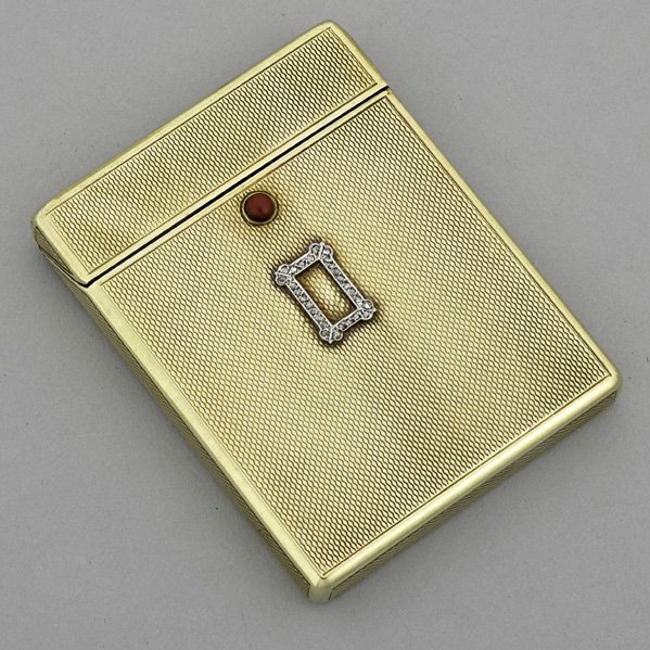 JEWELED 15K GOLD CARD CASE, ca. 1920: Rectangular, engine-turned surfaces, coral thumb press deploys hinged lid, rose cut diamond platinum ornament. 51.5 dwt. (80.1 gs.), 2 7/8" x 2 1/4". International bids and bids issuing from the State