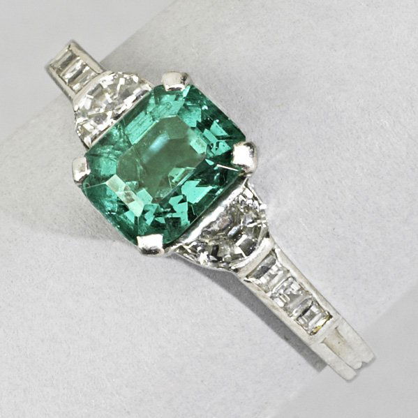 TIFFANY & CO. EMERALD AND DIAMOND RING: Bright step-cut emerald, 1.28 cts. by formula, flanked by half moon and square cut diamonds, approx. .50 ct. TW in platinum, ca. 1950. 2 dwt. (3.2 gs.), size 4 3/4