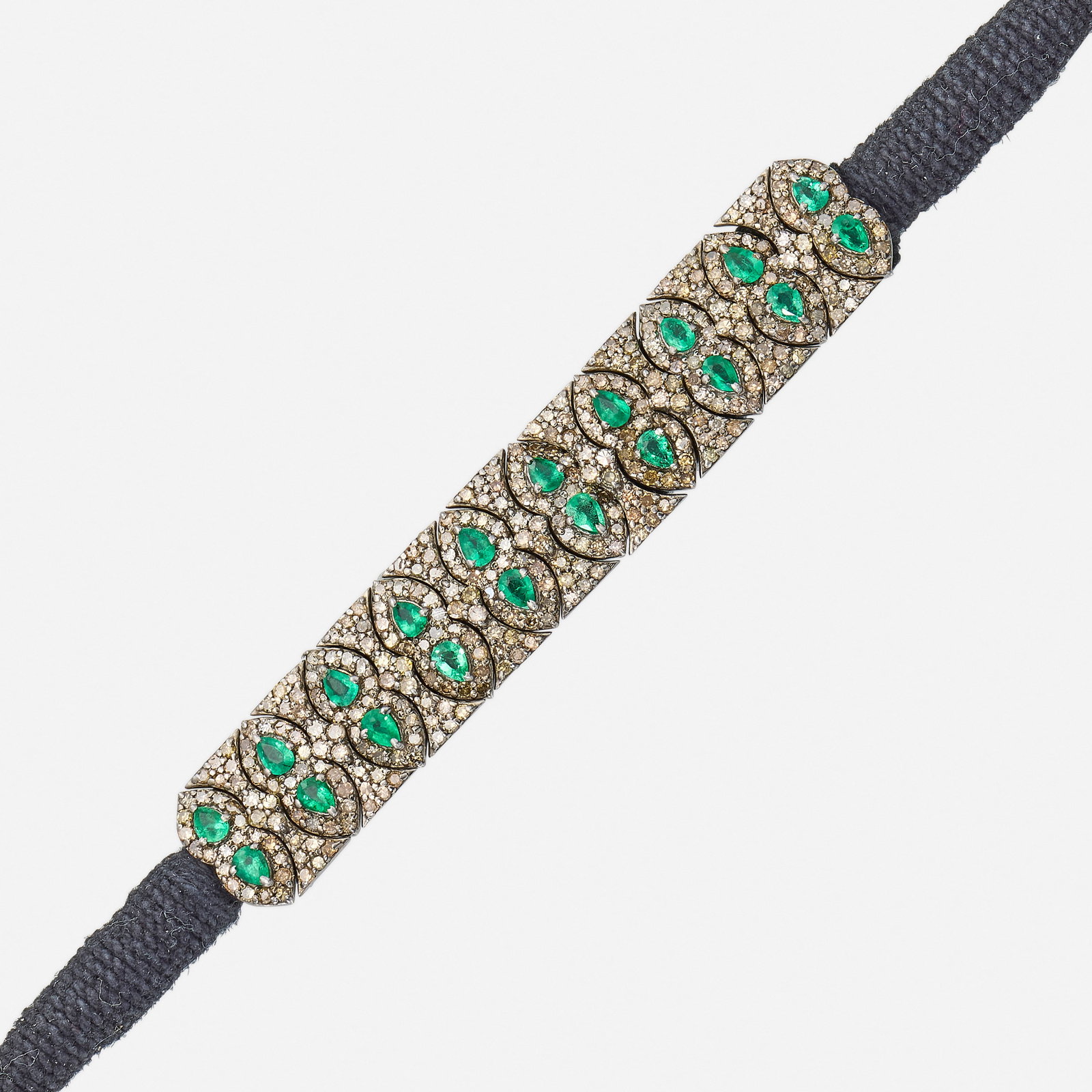 Emerald, diamond, silver, and cord bracelet: Emerald, diamond, silver, and cord bracelet The flexible bracelet, set with pear-shaped emeralds and single-cut diamond sections on a black cord Silver 8.50 x 0.50 in; Gross weight 12.0 dwts This work