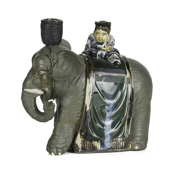SUMIDA GAWA POTTERY: Elephant-form candleholder with a child reading a book, early 20th c.; Illegible mark; 7 1/8" x 7 1/4" x 4 1/2"