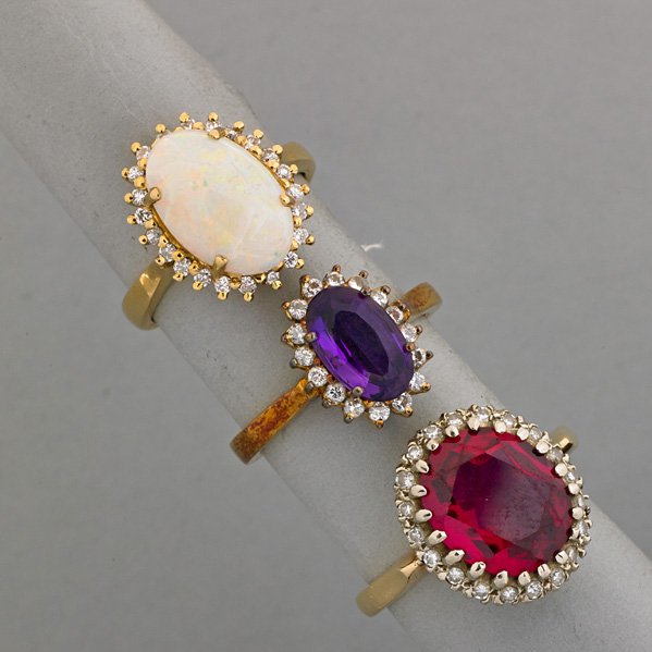 THREE JEWELED DIAMOND OVAL CLUSTER RINGS, 20th C.: Opal; Amethyst; Synthetic ruby; All 14k yg., diamonds approx..75 ct. TW; 9.4 dwt., size 5 1/2 - 8 1/2