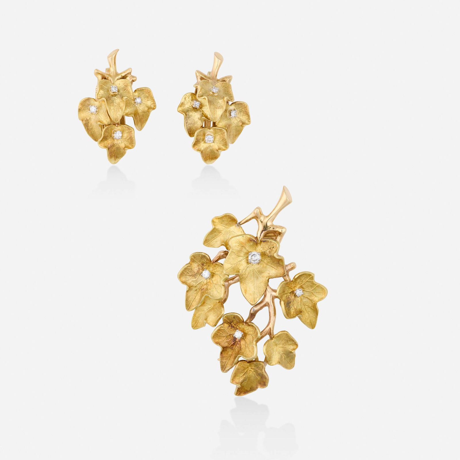 Cartier, Diamond and gold brooch and earrings: Cartier Diamond and gold brooch and earrings Each a cluster of leaves set with round brilliant-cut diamonds 14k yellow gold Signed Cartier, numbered to each example Brooch 2 x 1.375 in, earrings 1 x