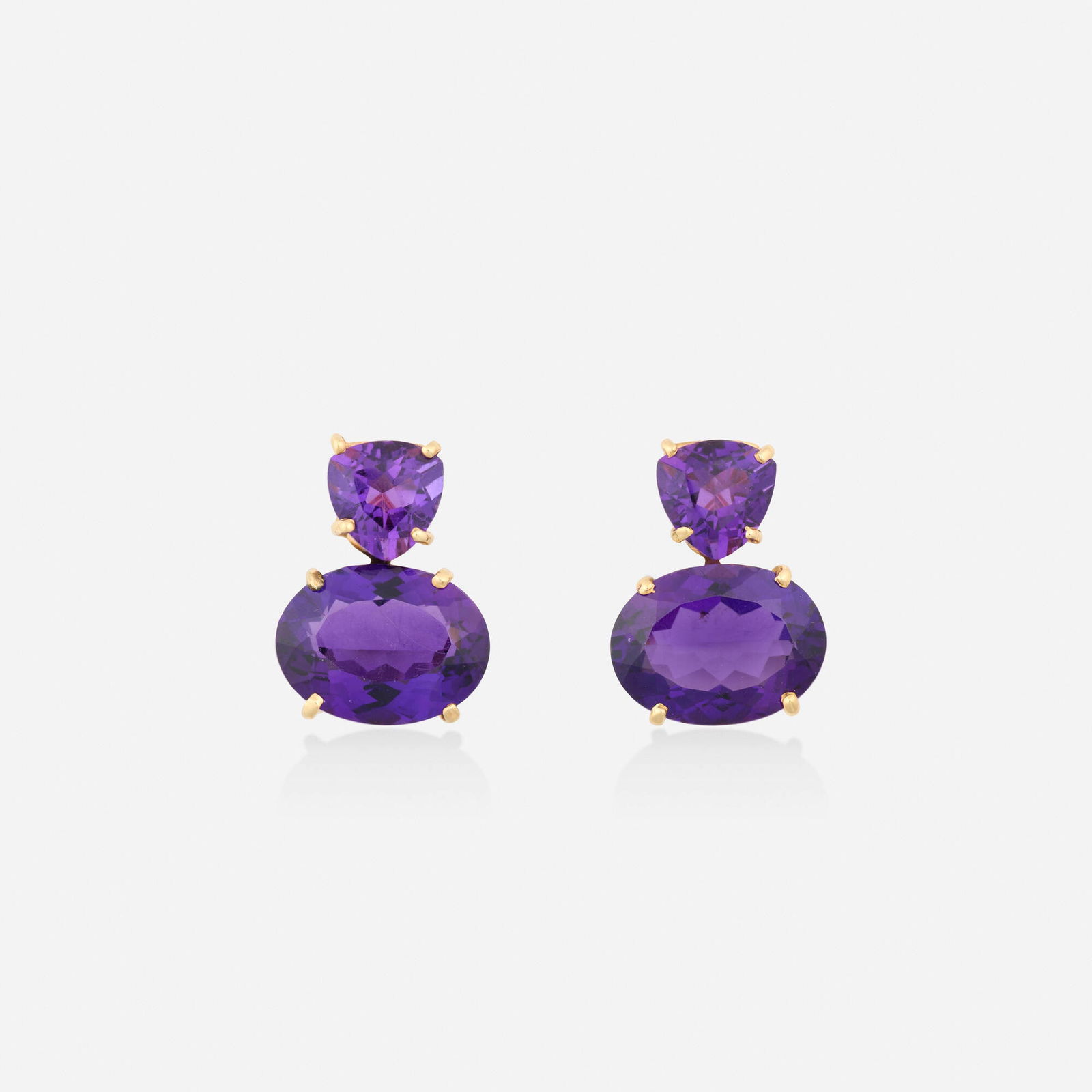 Amethyst and gold earrings: Amethyst and gold earrings Each set with a triangular and oval-cut amethyst 14k yellow gold 1 x 0.75 in; Gross weight 10.6 dwts This work will ship from Lambertville, New Jersey.