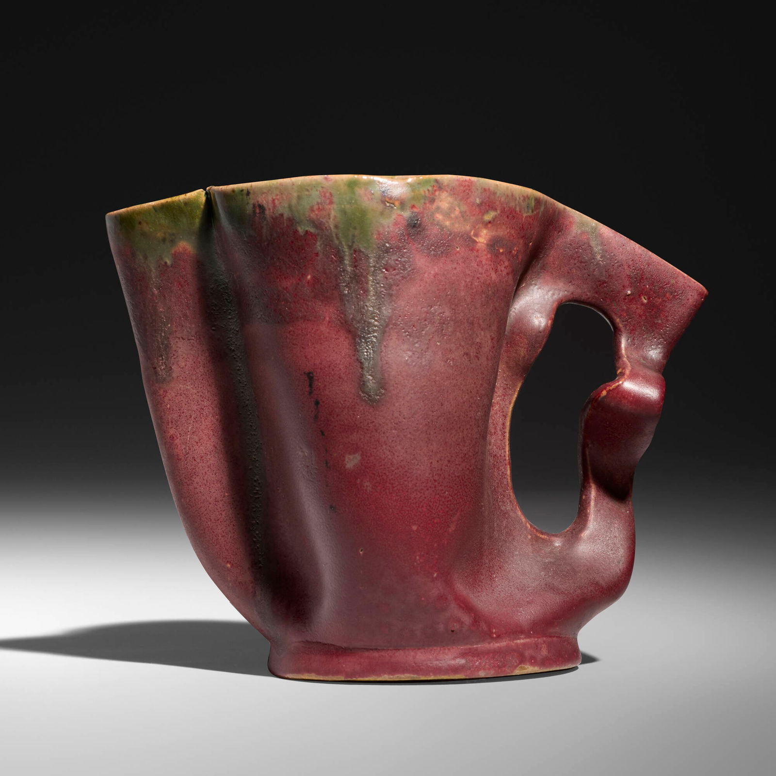 George E. Ohr, Pitcher: George E. Ohr Pitcher USA, 1898-1910 glazed earthenware 4.5 h x 6 w x 3.5 d in (11 x 15 x 9 cm) Pitcher features a lobed rim, a cut-out and crimped handle, and a matte raspberry glaze with emerald