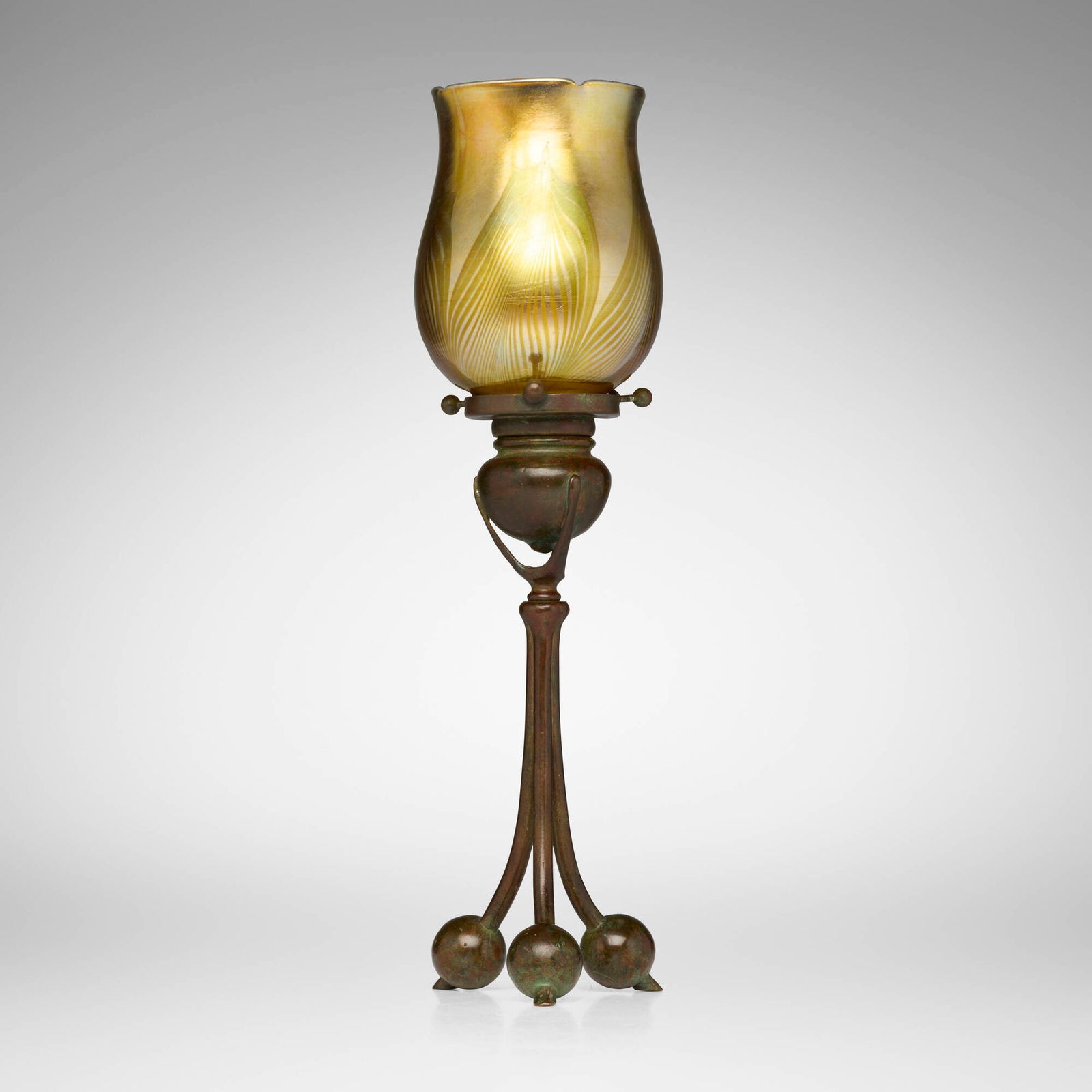 Tiffany Studios, Tripod candlestick with pulled-feather shade: Tiffany Studios Tripod candlestick with pulled-feather shade USA, c. 1910 patinated bronze, hand-blown Favrile glass 14 h x 3.75 dia in (36 x 10 cm) Etched to shade 'L.C.T. Favrile'. Impressed to
