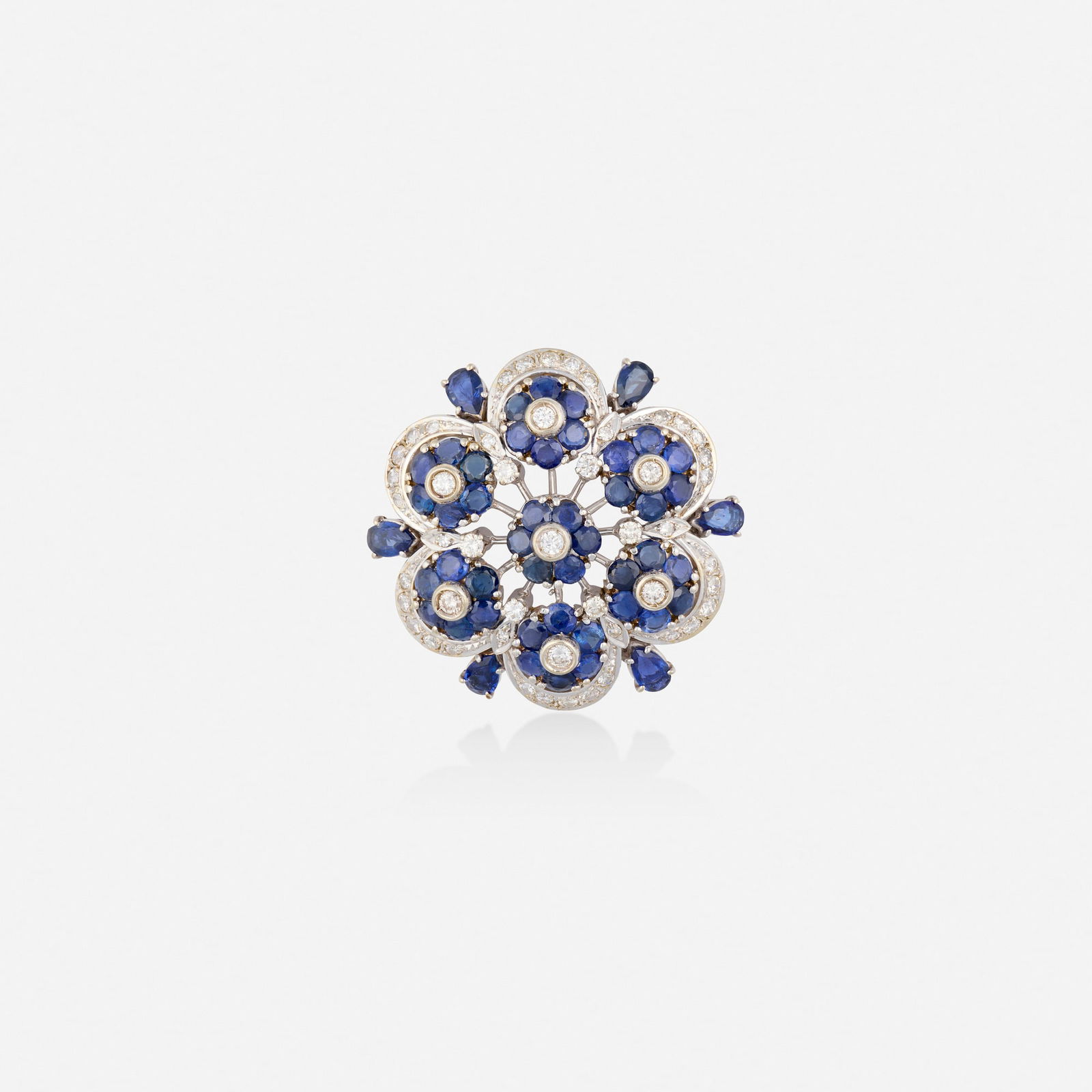 Sapphire, diamond, and gold brooch: Sapphire, diamond, and gold brooch Of floral design, set with pear and circular-cut sapphires, round brilliant and single-cut diamonds 18k white gold-plated yellow gold 1.375 in; Gross weight 10.4
