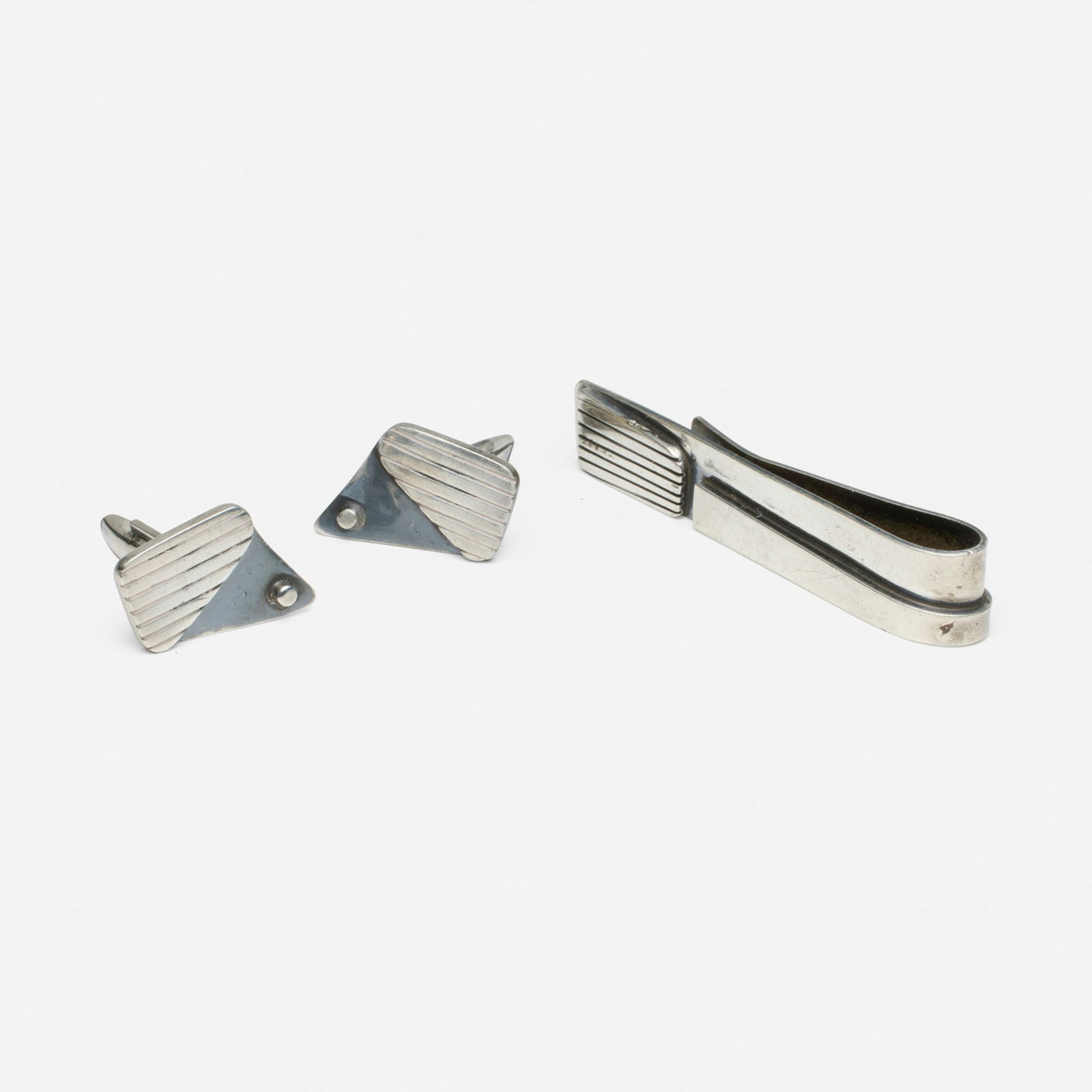 Ed Wiener, Sterling silver cufflinks and tie bar: Ed Wiener Sterling silver cufflinks and tie bar Of modernist design Sterling silver Signed Ed Wiener to each example 2.625 x 0.50 in and 0.75 x 0.875 in; Gross weight 27.1 dwts Pr