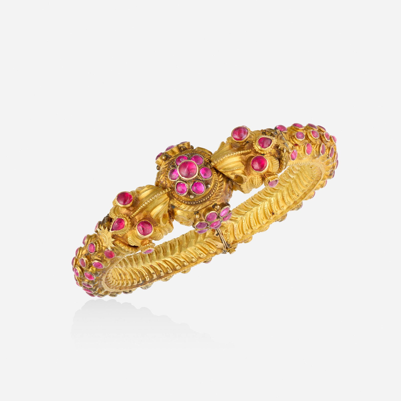 Indian, Ruby and gold plate bracelet: Indian Ruby and gold plate bracelet The hinged bangle of ornamental design, set with cabochon rubies; 1990s Gold plate Inner circ. 6.75 in, width 0.75 in; Gross weight 51.1 dwts This work