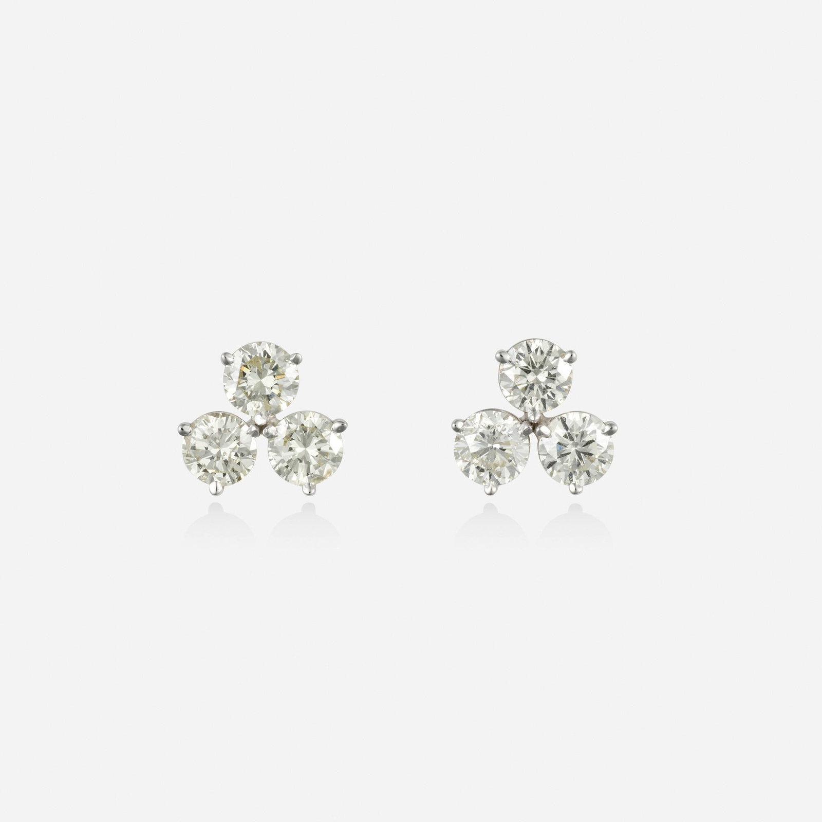 Diamond and white gold earrings: Diamond and white gold earrings Each set with three round brilliant-cut diamonds 14k white gold 0.50 in; Gross weight 1.9 dwts This work will ship from Lambertville, New Jersey.