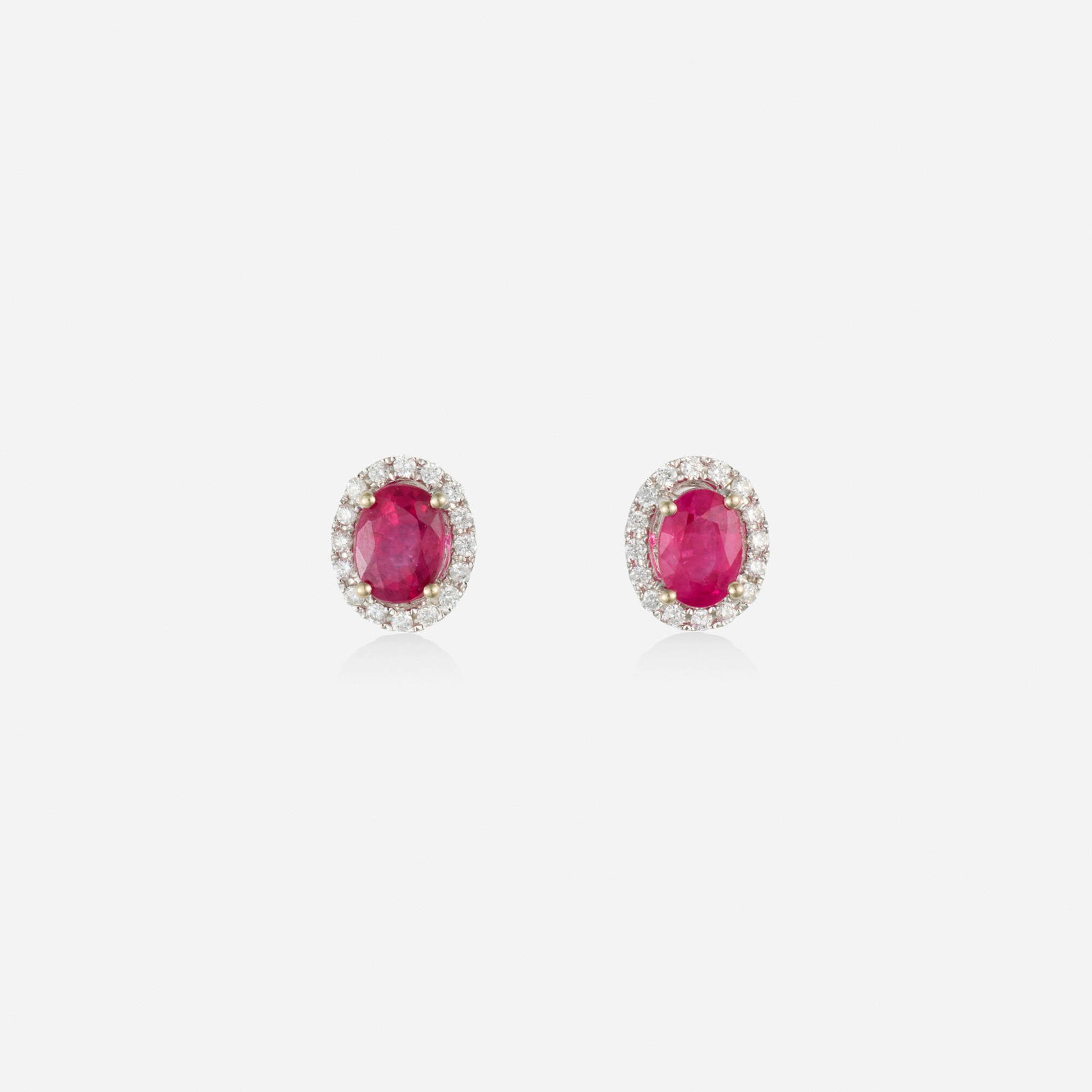 Ruby, diamond, and white gold earrings: Ruby, diamond, and white gold earrings Each set with an oval-cut ruby framed by round brilliant-cut diamonds 14k white gold 0.50 x 0.25 in; Gross weight 1.4 dwts This work will ship from Lambertville,