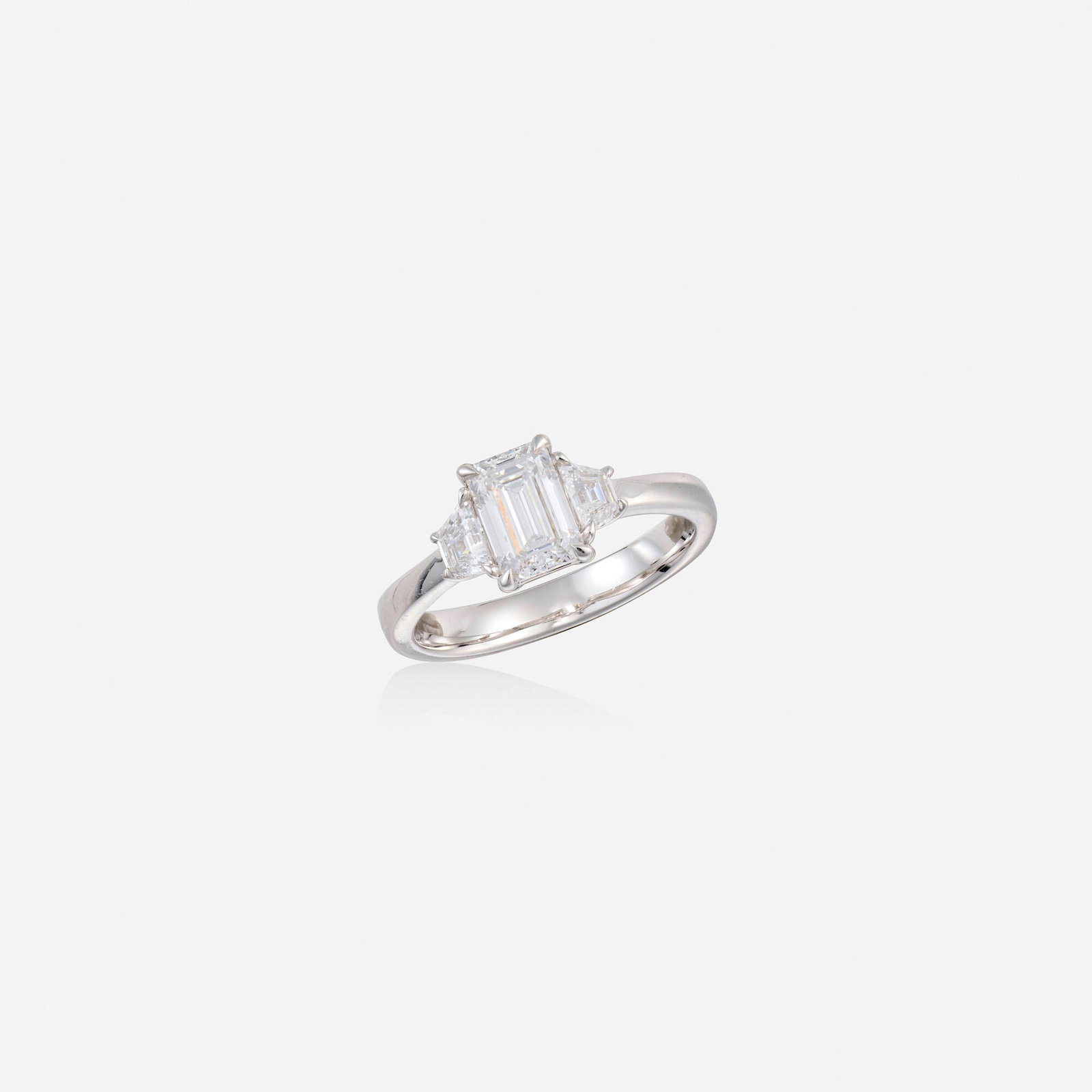 Diamond and white gold ring: Diamond and white gold ring Set with an emerald-cut diamond, flanked by trapezoidal-cut diamonds 14k white gold Ring size 6.50; Gross weight 2.2 dwts This work will ship from Lambertville, New Jersey.