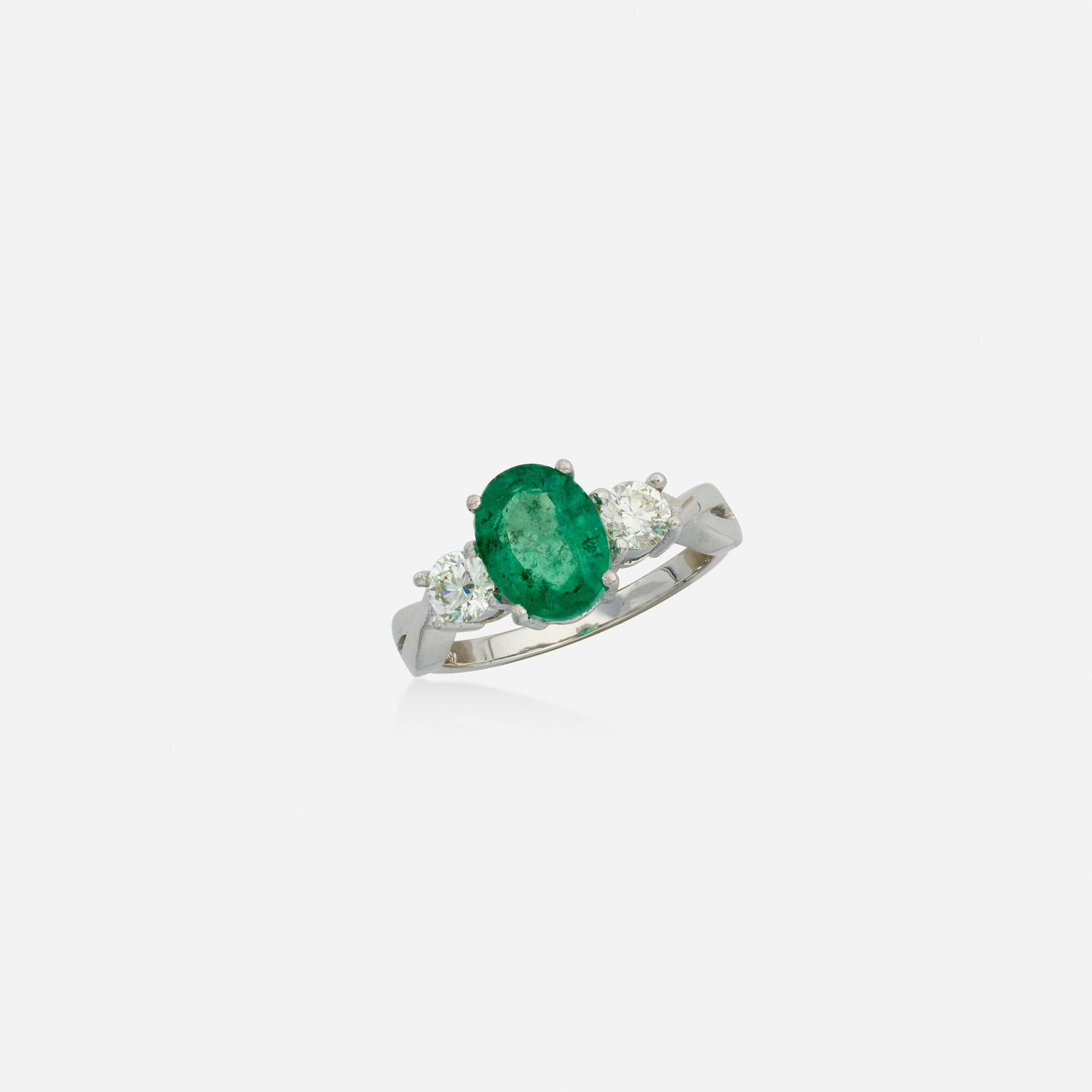 Emerald, diamond, and white gold ring: Emerald, diamond, and white gold ring Set with an oval-cut emerald, flanked by round brilliant-cut diamonds 18k white gold Ring size 7; Gross weight 2.5 dwts This work will ship from Lambertville,