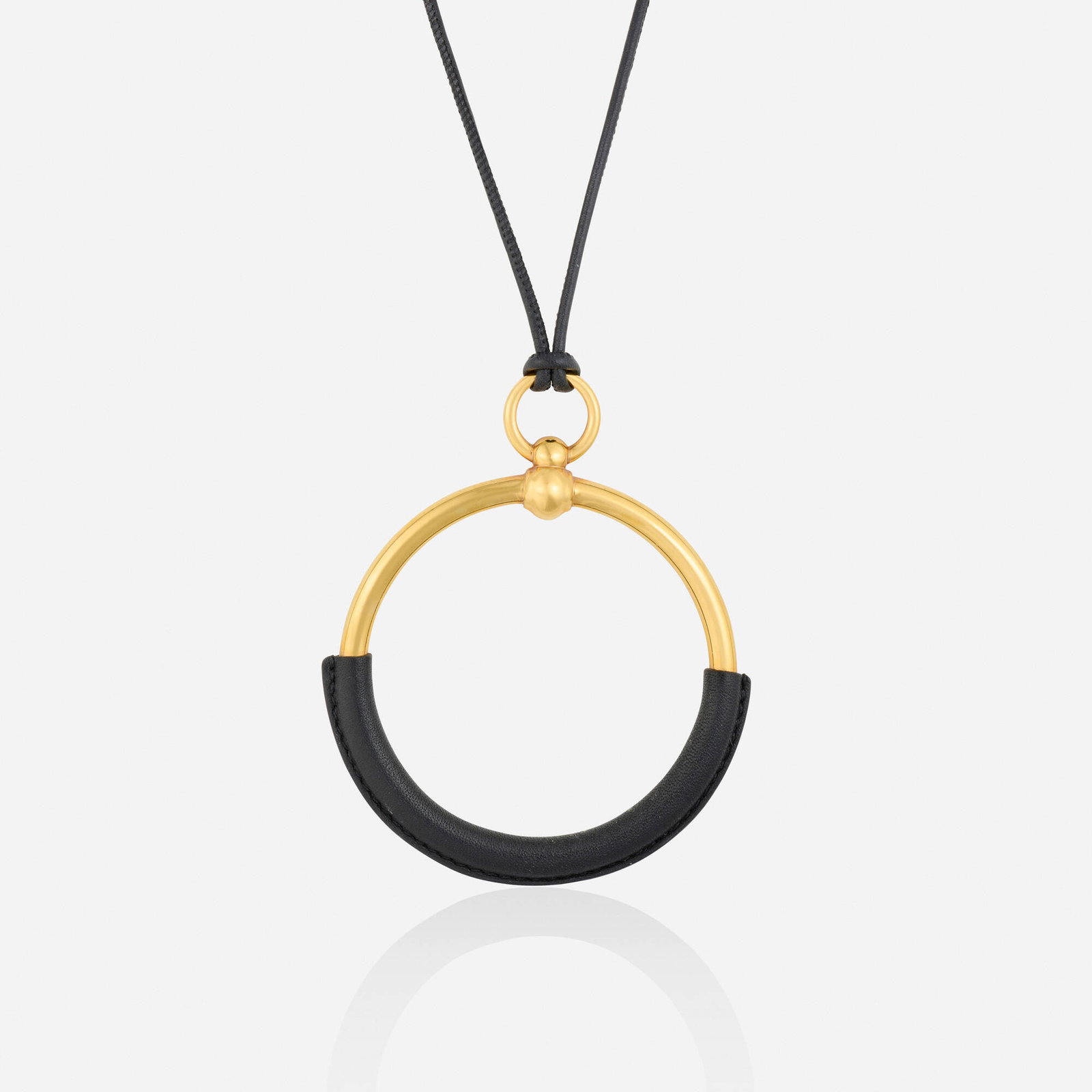 Hermes, 'Loop Grande' necklace: Hermes 'Loop Grande' necklace Designed with an oversized hoop pendant covered in leather, suspended from the black cord Gold tone metal Signed Hermes Necklace approx. 31 in, pendant 3.50 x 2.75 in