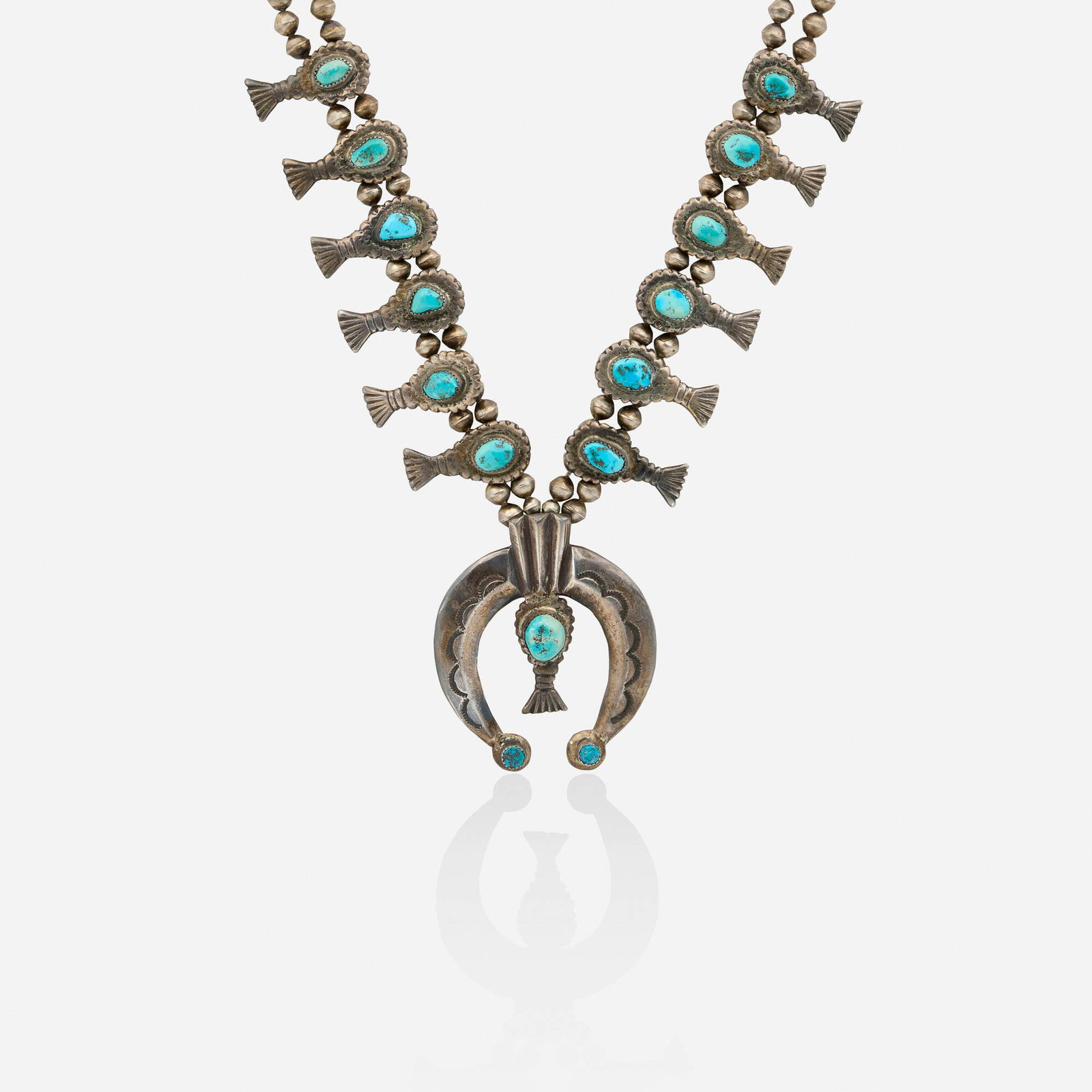 Turquoise and silver necklace: Turquoise and silver necklace Of tumbled turquoise suspending blossom pendants with silver beads Silver 26 in; Gross weight 138.5 dwts This work will ship from Lambertville, New Jersey.
