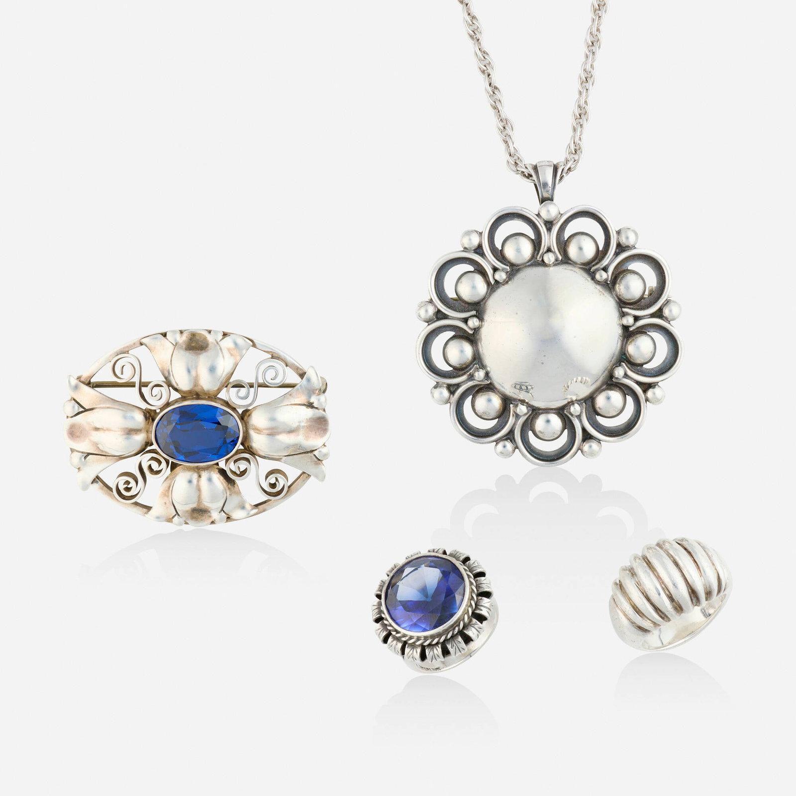 The Kalo Shop, Group of sterling silver jewelry: The Kalo Shop Group of sterling silver jewelry Comprising a circular pendant brooch on chain, a floral brooch set with an oval-cut synthetic blue spinel, a ridged ring, and a ring set with oval-cut sy