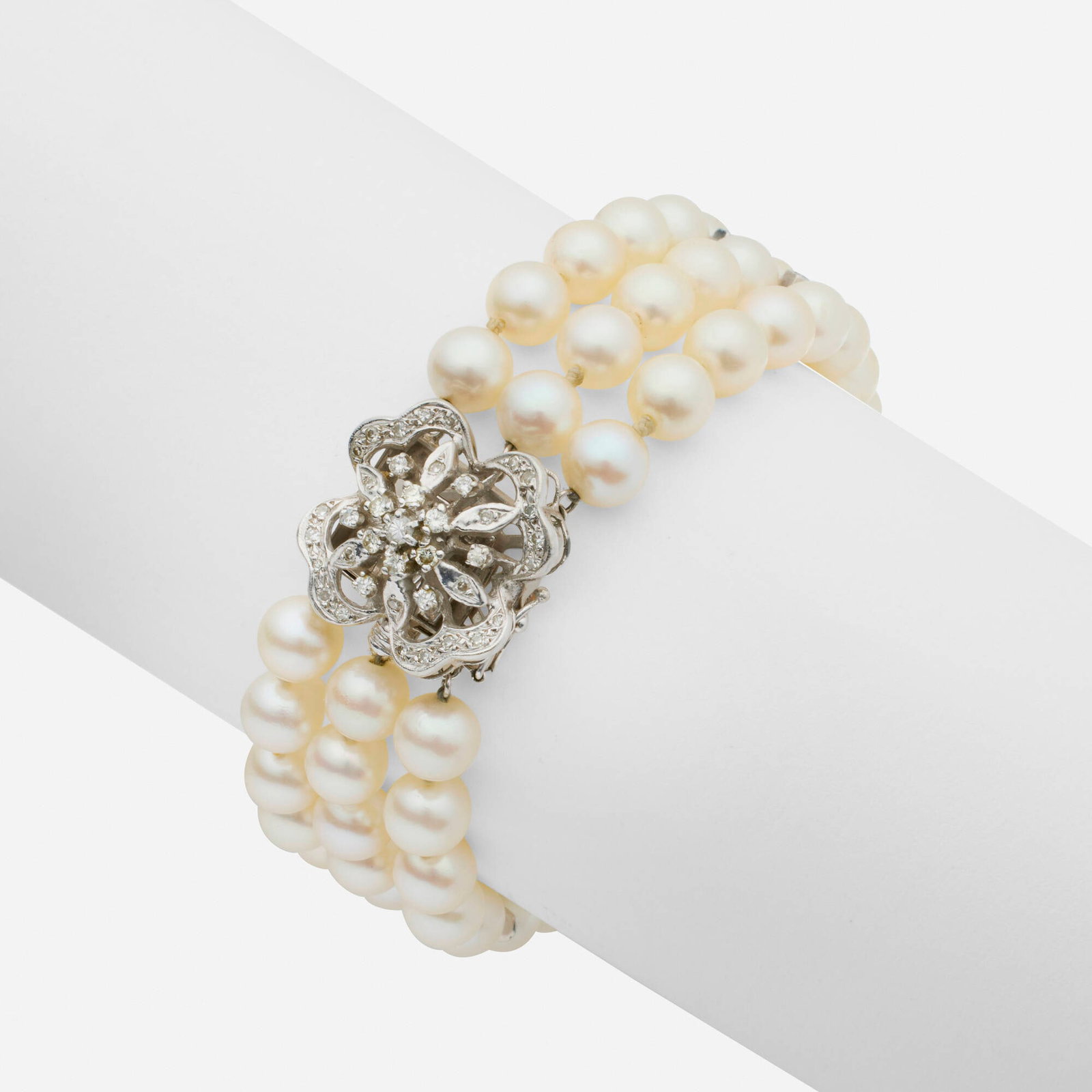 Cultured pearl, diamond, and white gold bracelet: Cultured pearl, diamond, and white gold bracelet Strung with three strands of cultured pearls with single-cut diamond spacer bars, the clasp set with round brilliant and single-cut diamonds 14k white 