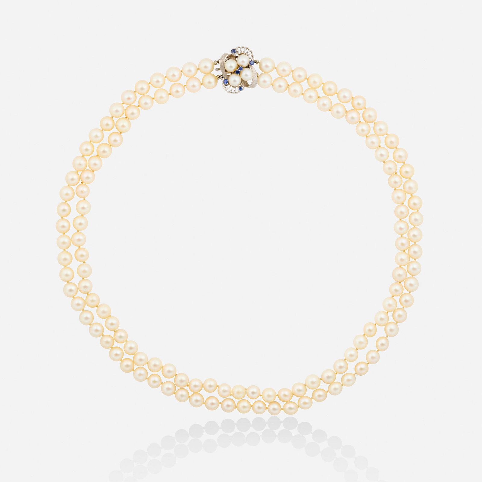 Cultured pearl, sapphire, and white gold necklace: Cultured pearl, sapphire, and white gold necklace Strung with two strands of cultured pearls, the clasp set with circular-cut sapphires and cultured pearls 14k white gold 23.25 in; Gross weight 76.7 d