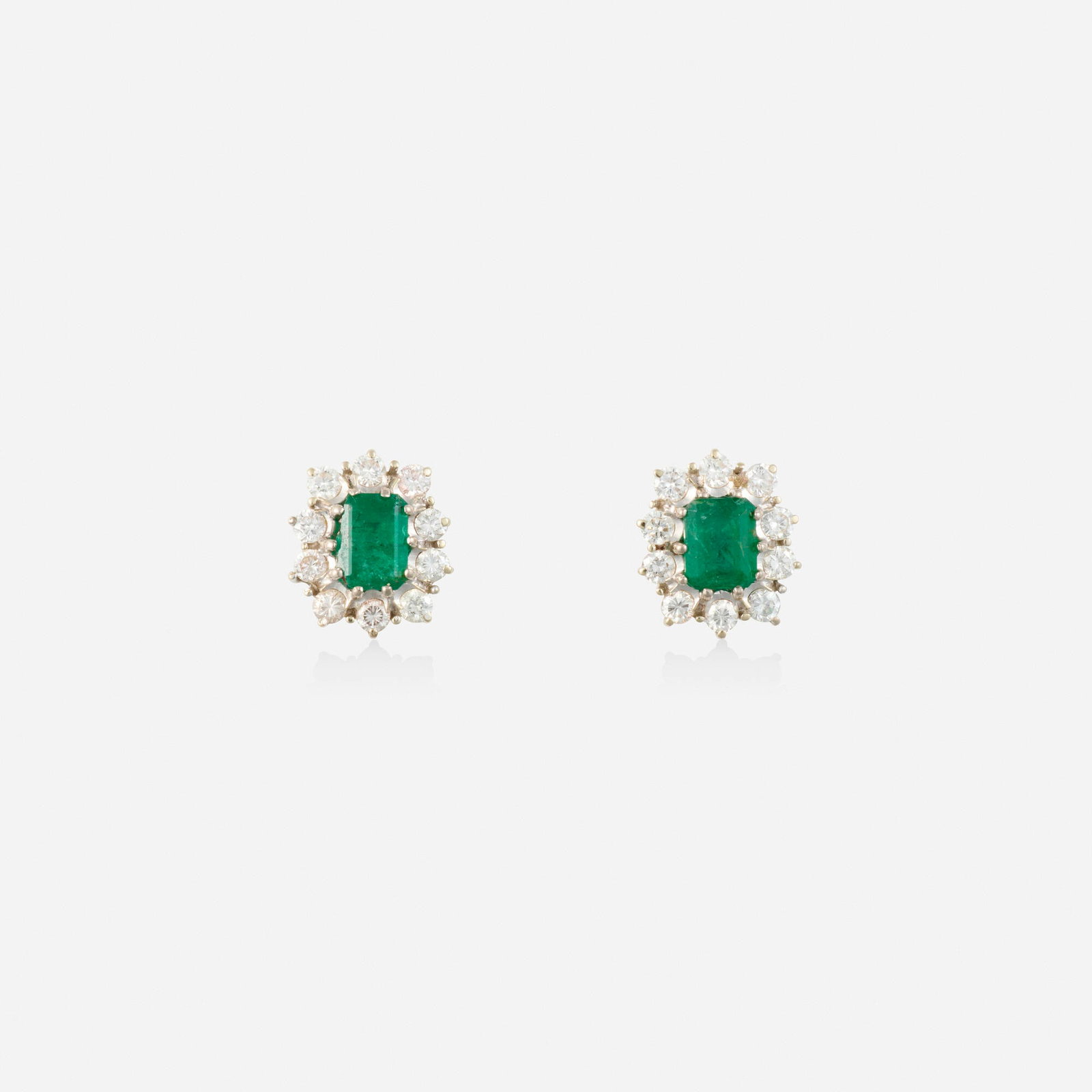 Emerald, diamond, and white gold earrings: Emerald, diamond, and white gold earrings Each set with an emerald-cut emerald, framed by round brilliant-cut diamonds White gold 0.375 x 0.25 in; Gross weight 1.6 dwts This work will ship from