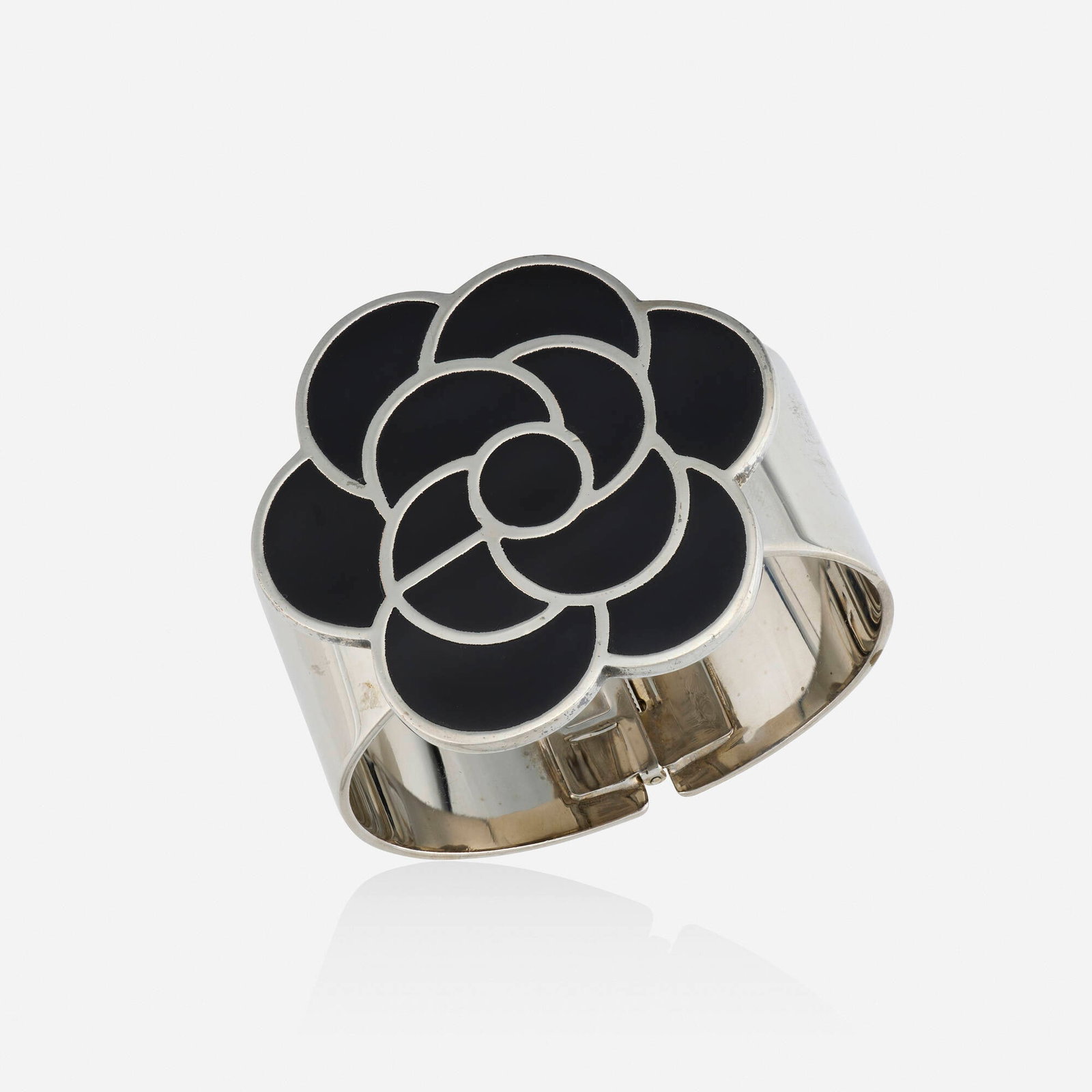 Chanel, 'Camellia' enamel and metal bracelet: Chanel 'Camellia' enamel and metal bracelet The hinged bangle of floral design with black enamel; part of the 1998 Collection by Karl Lagerfeld Palladium-plated metal Signed Chanel Inner circ. 6.2