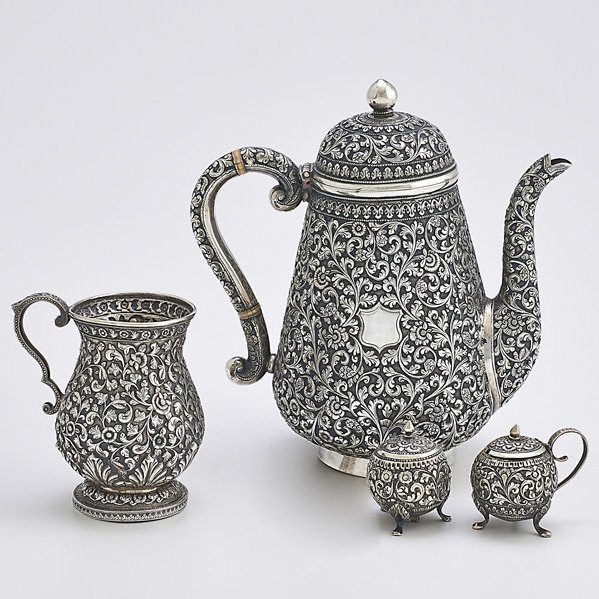FINE INDO-PERSIAN SILVER HOLLOWARE: Four pieces; gourd-shaped coffee pot on ring foot with ivory insulators, 9 3/4"; Bulbous mug with double scroll incised floral handle, 4 3/4", and Spherical footed salt and pepper shakers, 2 1/4", all