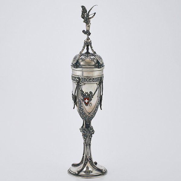 SWISS 800 SILVER COVERED SHOOTING TROPHY CUP: Heraldic angel cover with mistletoe, lion mask column suspends enameled shields, St. Gallen, 1904; Marked Vereinigte Goldschmiede St. Gallen and control marks; 18 3/4"; 22 OT