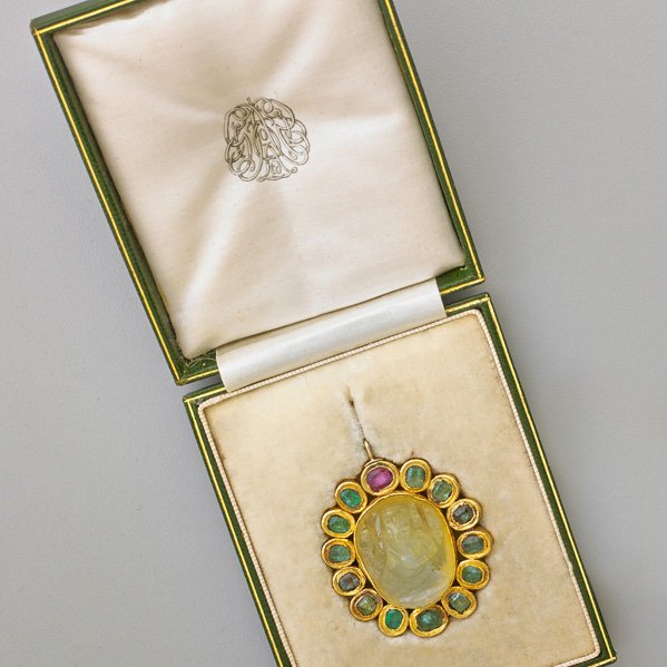 INDIAN JEWELED GANESHA AMULET: Jade surrounded by Kundan set emeralds and a ruby, 1 3/4" x 1 1/2", 19th c. In fitted case.