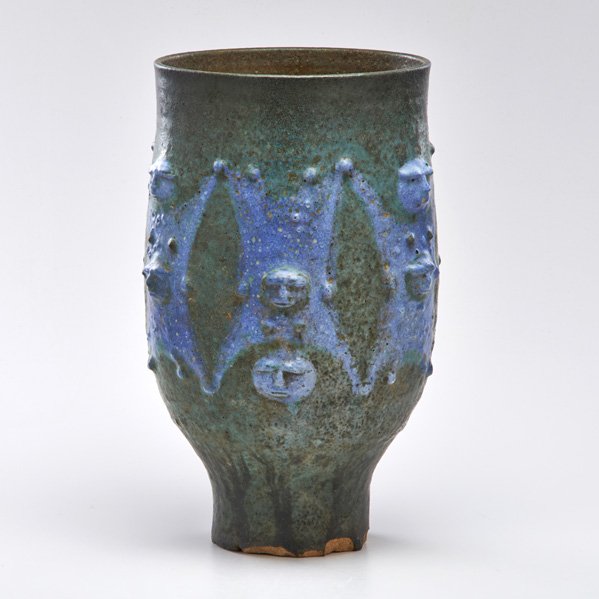 EDWIN AND MARY SCHEIER: Tall footed coupe with peaking figures in gunmetal and blue glazes, Green Valley, AZ; Illegible mark; 15" x 8 1/2" dia.