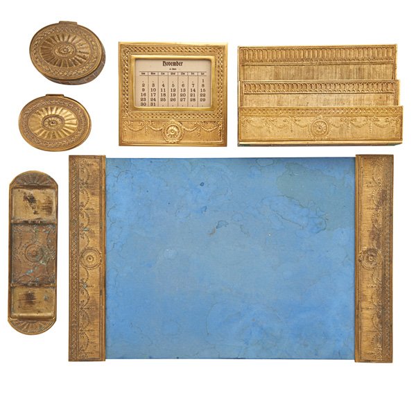 TIFFANY STUDIOS DESK SET: Seven pieces in the 'Adams' pattern, early 20th c.: pair of blotter ends, letter rack, inkwell, calendar, oval box and pen tray; Stamped Tiffany Studios New York; Letter rack: 6" x 9 1/4" x 2 1/2"