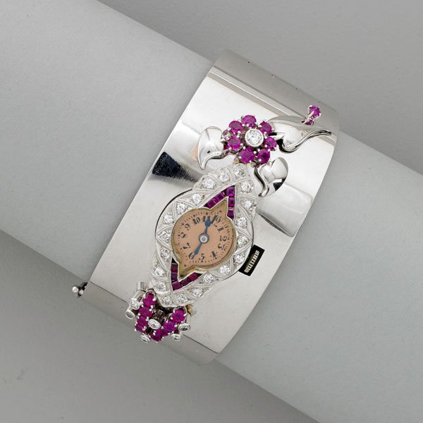 RETRO DIAMOND, RUBY AND WHITE GOLD BRACELET WATCH: Bright 14k wg. hinged bangle with ruby and diamond floral and geometric element inset Art Deco diamond and ruby platinum watch, stem wound, stem set makers element, Swiss, 17 jewels, 3 adj.; Diamonds