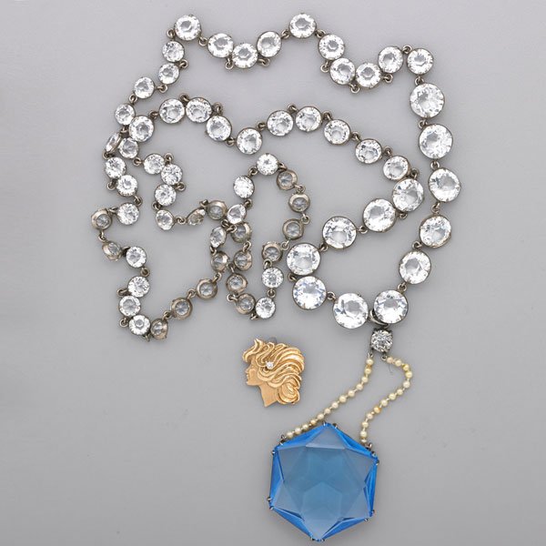ART DECO PASTE SAUTOIR AND GOLD BROOCH: Clear faceted pastes in chrome plated settings, suspends blue hexagonal paste in silver mount, 22"; Art Nouveau style 14k yg. female profile brooch with pendant bails, set with approx. .07 ct. round b