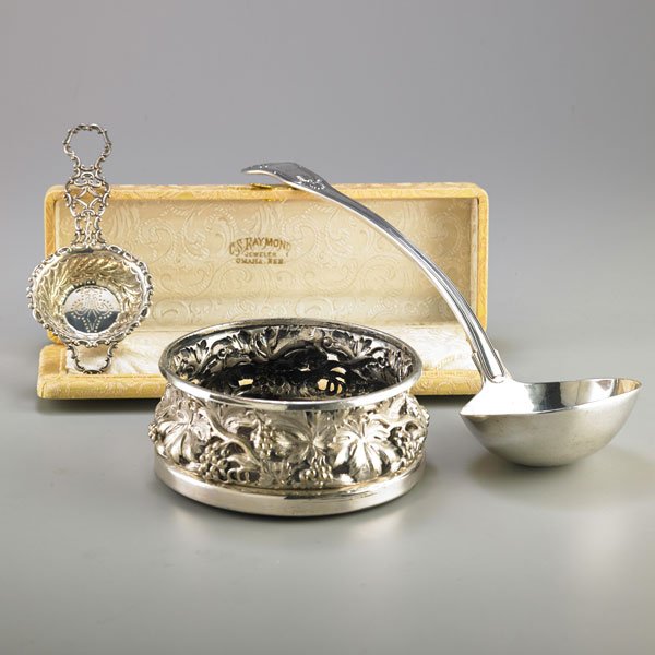 AMERICAN OR ENGLISH STERLING AND SILVER PLATE: Three pieces: Shell handled sterling soup ladle, Harrison Bros., London, 1820, 13 1/2"; Gorham sterling tea strainer, 1895, 6 3/4" in C.S. Raymond, Omaha brocade box; Silver-plated wine bottle coaster