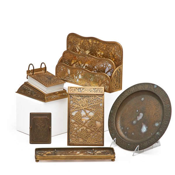 TIFFANY STUDIOS Six desk-set pieces: TIFFANY STUDIOS Assembled six-piece desk set in assorted patterns, New York, 1900s: Grapevine letter holder, pen tray, and notepad, Pine Needle calendar, Chinese paper clip, tray #1787; Partial gilt m