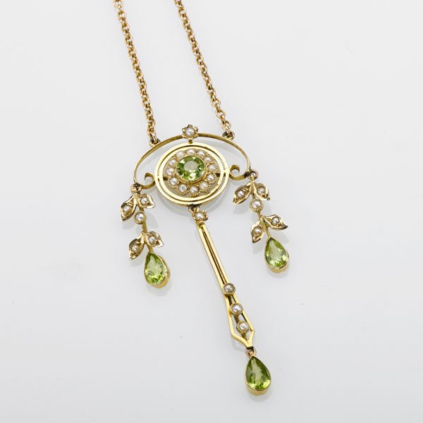 EDWARDIAN PERIDOT AND SEED PEARL LAVALIERE: Central round faceted peridot and seed pearl flower head suspend seed pearl set foliate drops, terminated by pear shaped faceted peridots, 9 ct. yg., ca. 1905; 15", drops 2 1/4"; 3.7 dwt.