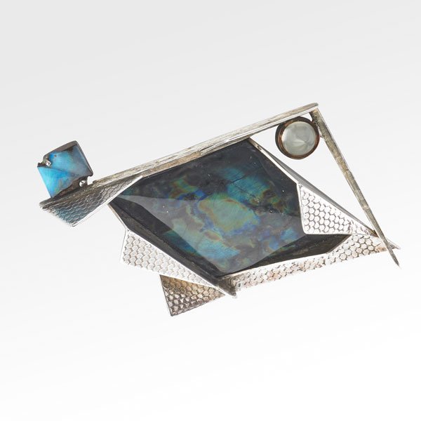 ARTISANAL SILVER AND GEMSTONE BROOCH: Geometric brooch with central trapezoidal labradorite within crisp creases of embossed textured silver, accented by bezel set moonstone bullet and a fantasy boulder opal, in the style of Margaret de P