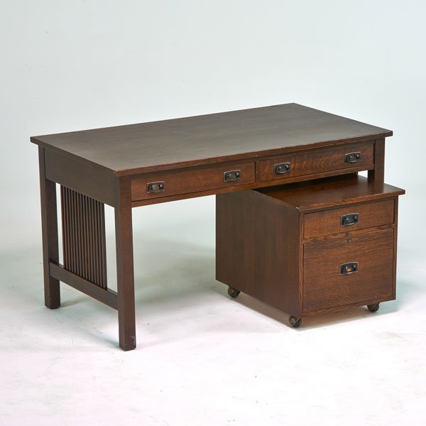 STICKLEY BY E. J. AUDI: Contemporary two-drawer spindled desk in the style of Gustav Stickley with matching rolling two-drawer tabouret, Manlius, NY, 1990s; Quartersawn oak, patinated metal; Branded mark and metal tag; Desk 