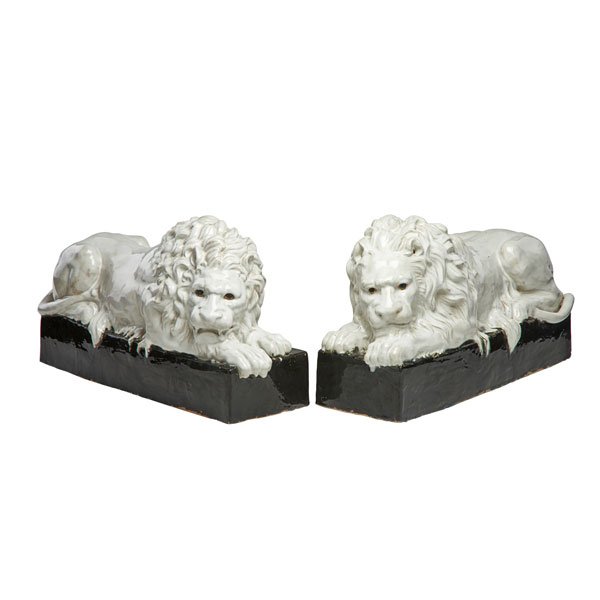 PAIR OF GLAZED EARTHENWARE LIONS: Mounted on plinths, Continental, early 20th c.; 11 3/4" x 21”