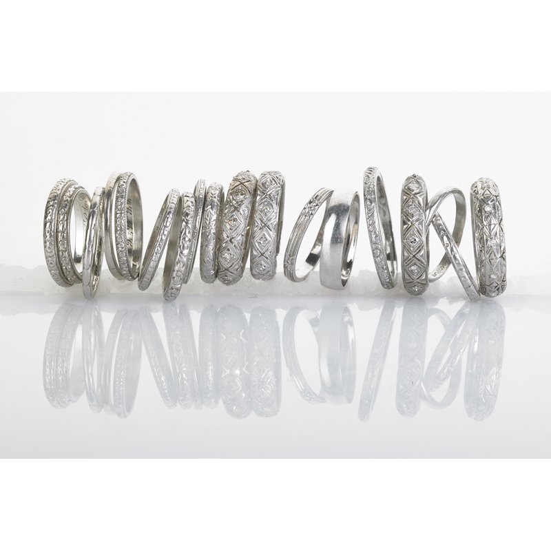 EIGHTEEN ART DECO PLATINUM WEDDING BANDS: Four pierced and engraved eternity bands with diamonds; Fourteen largely embossed or chased guard rings. Size 5 - 9 3/4. 33 dwt. Property from the collection of Gray Davis Boone.