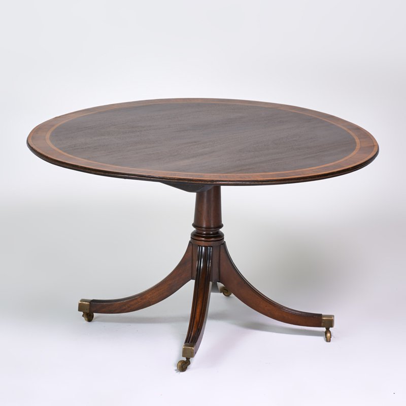 ENGLISH: "Tillman" round pedestal dining table with five extensions, mid-20th c.; Mahogany with satinwood banding; 19 1/2" x 50 1/2" without extensions, 66" dia. with extensions