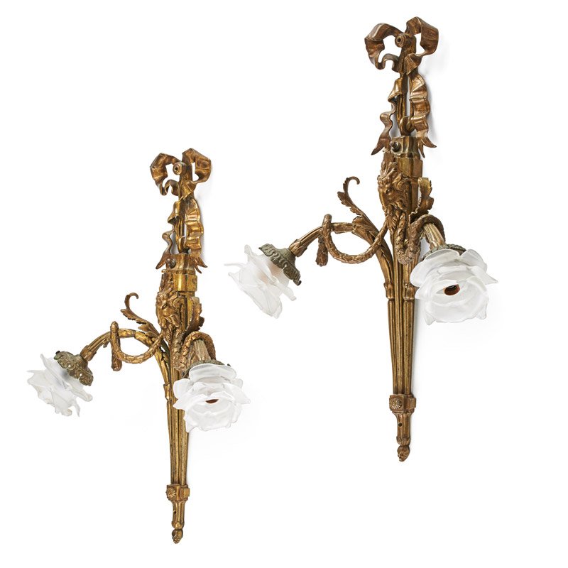 PAIR OF LOUIS XVI GILT METAL SCONCES: Each with two arms, cast with scrolling ribbon and goat's head, frosted glass floral shades, 19th/20th c.; 23" x 16 1/2"