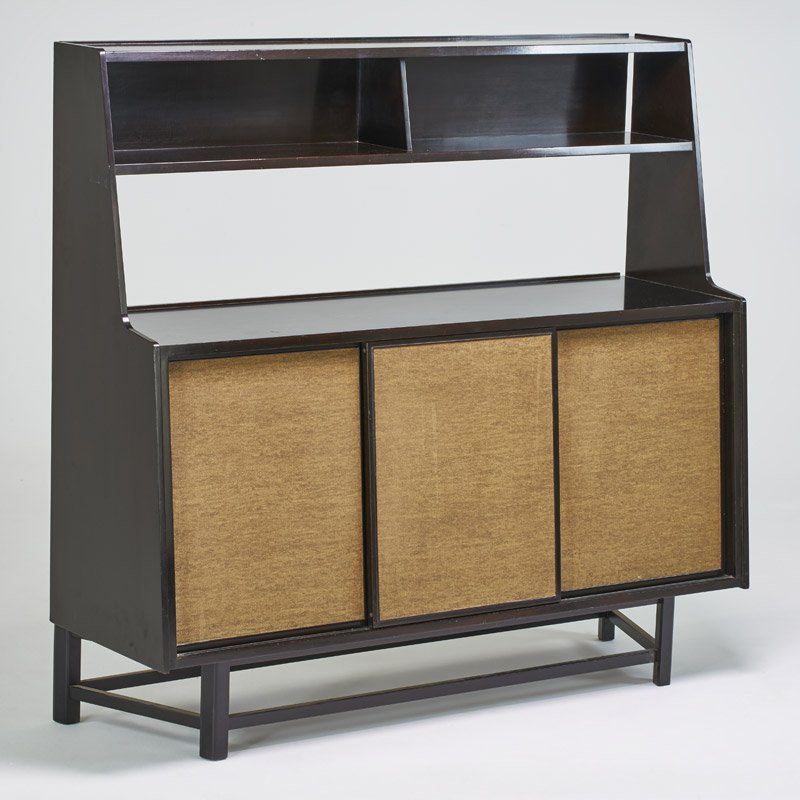 EDWARD WORMLEY; DUNBAR: Sliding door cabinet, Berne, IN, 1950's; Stained mahogany and dyed grass cloth doors; Metal label; 58" x 61" x 19"