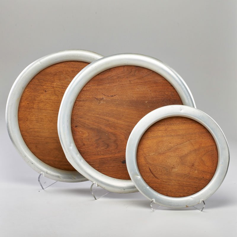 RUSSEL WRIGHT: Three spun aluminum trays with walnut bottoms, USA, ca. 1930; Two marked; Largest: 17" dia.