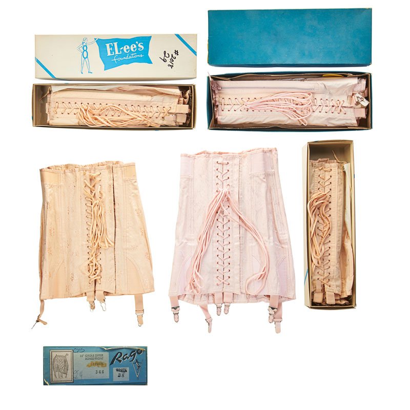 COLLECTION OF TWELVE VINTAGE GIRDLES: Comprising pink or white laced girdles with flat sewn seams and all around paneling, metal garters, ca. 1940-1950. Newark, New Jersey. In Rago & El-Lees vintage boxes.