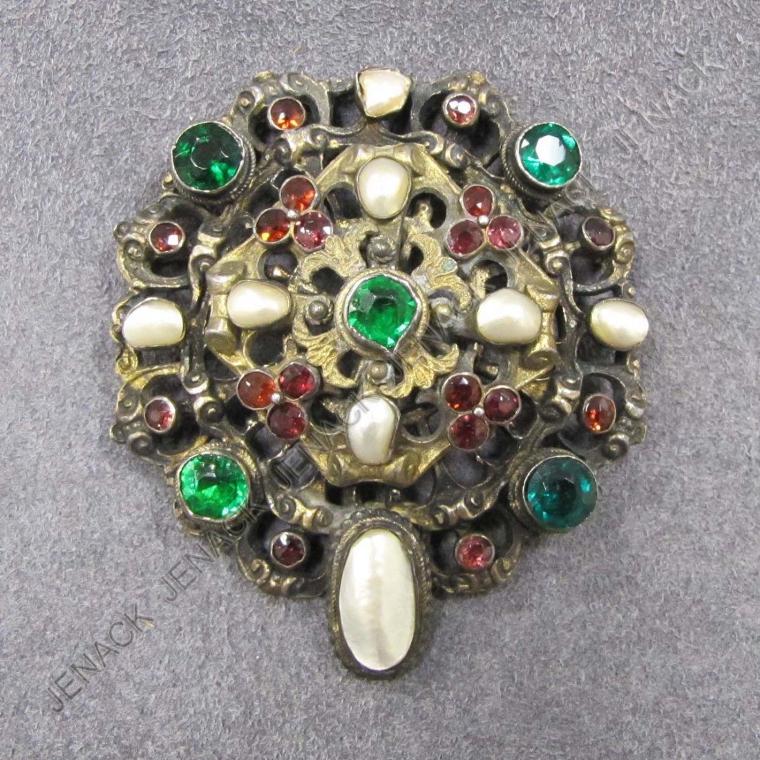 RENAISSANCE REVIVAL STYLE GILT SILVER BROOCH: RENAISSANCE REVIVAL STYLE GILT SILVER BROOCH WITH MOTHER-OF-PEARL BAROQUE PEARLS, GARNETS AND GREEN PASTE STONES. DIAMETER 2 1/8"; GROSS WEIGHT 1.39 OZT