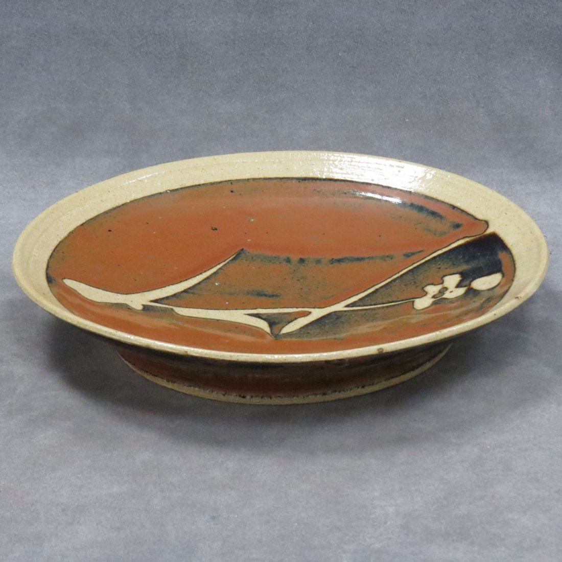 SHOJI HAMADA STONEWARE PLATE: SHOJI HAMADA STONEWARE PLATE WITH WAX RESIST SUGAR CANE DESIGN ON TEA DUST GLAZE GROUND. DIAMETER 10 1/2"