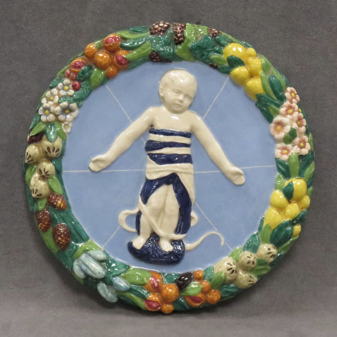 DELLA ROBBIA STYLE ITALIAN POTTERY PLAQUE: DELLA ROBBIA STYLE ITALIAN POTTERY AND FAIENCE PLAQUE, ARTIST SIGNED AND NUMBERED. DIAMETER 10"