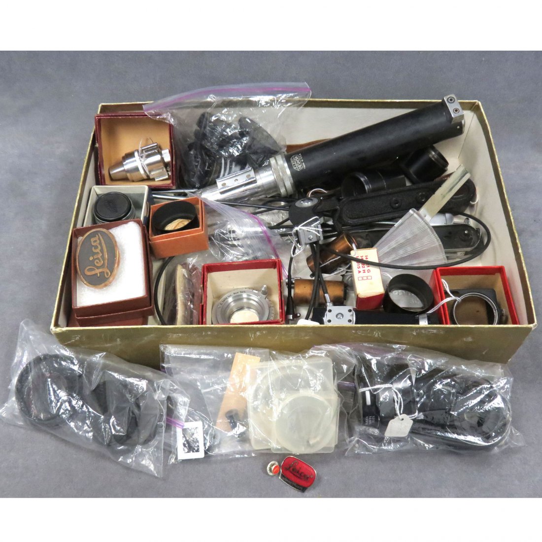 LOT ASSORTED VINTAGE LEICA ACCESSORIES: LOT ASSORTED VINTAGE LEICA ACCESSORIES INCLUDING FILTERS, RANGE FINDERS, BELT BUCKLE, LENS HOODS AND COVERS, FLASH GUN, ETC