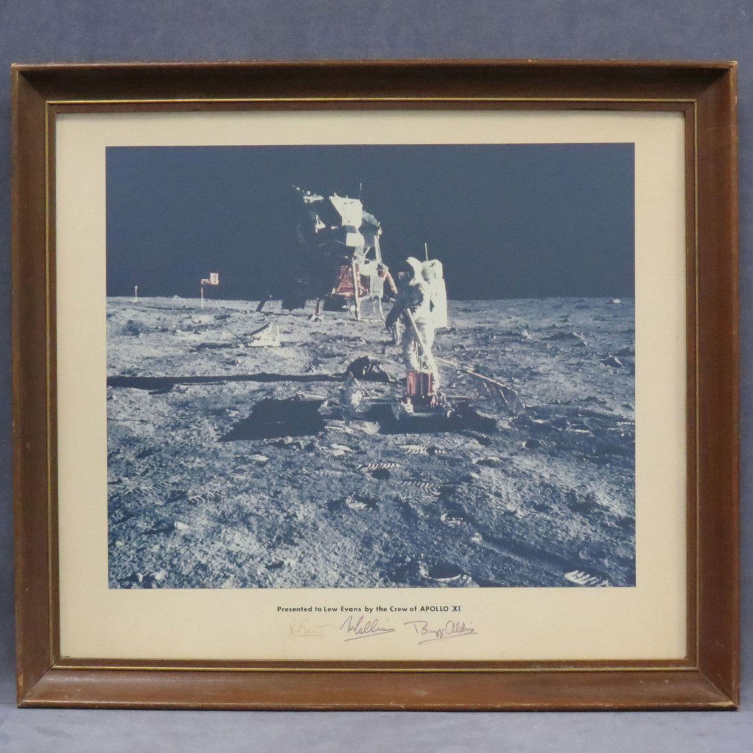 APOLLO XI MOON WALKERS COLOR LUNAR SURFACE PHOTO: APOLLO XI MOON WALKERS COLOR LUNAR SURFACE PHOTO (LAID DOWN AND PRINTED ON MAT), "PRESENTED TO LEW EVANS BY THE CREW OF APOLLO XI", SIGNED BUZZ ALDRIN, NEIL ARMSTRONG, AND MICHAEL COLLINS. SIGHT 19 1/